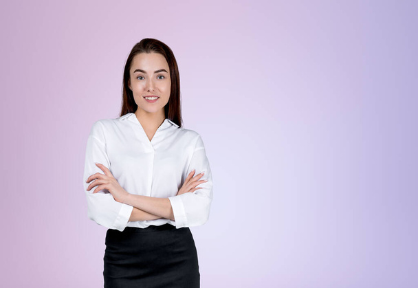 Smiling attractive businesswoman wearing formal wear is standing crossed arms near empty purple wall in background. Concept of model, successful business person, student, confidence - Foto, Imagem