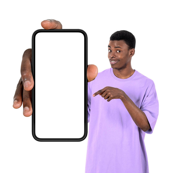 Black young man smiling, finger pointing at large smartphone mock up copy space screen, isolated over white background. Concept of social media and online network - Photo, Image