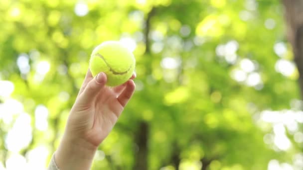 公園でアクティブなゲームをプレイ。木製のラケットでボールを打つ。テニスラケットを手にした女性の手を閉じる。天気の良い日に趣味やレクリエーション。アウトドアスポーツレジャー活動 - 映像、動画