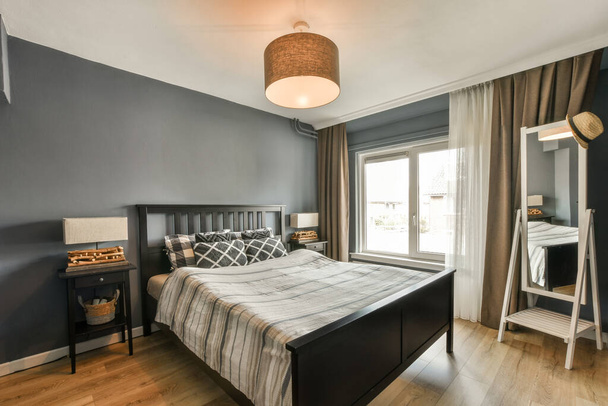 a bedroom with blue walls and wood flooring, including a black headboard on the side of the bed - Foto, immagini