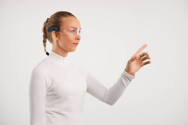 jong vrouw dragen smartglasses gebaren tegen witte achtergrond - Foto, afbeelding