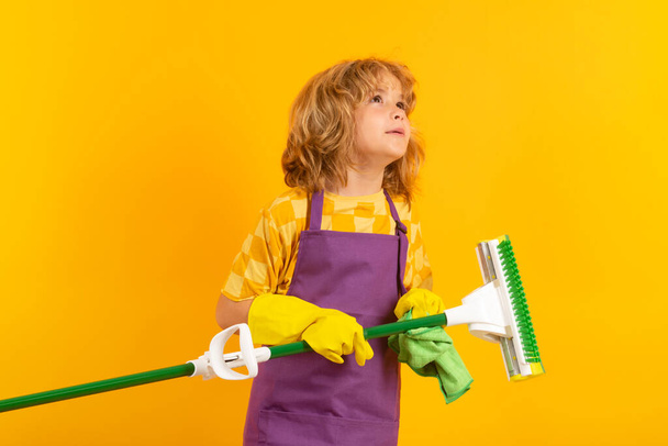 Retrato de limpieza infantil, crecimiento conceptual, desarrollo, relaciones familiares. Concepto de limpieza doméstica y del hogar. Uso infantil de plumero y guantes para la limpieza. Estudio aislado fondo - Foto, Imagen
