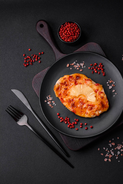 Filete de pollo a la parrilla en forma de filete con tomates, piña y queso sobre un fondo de hormigón oscuro - Foto, Imagen