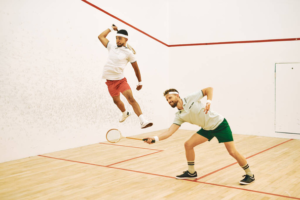 Trzymaj się na nogach. dwóch młodych mężczyzn gra w squasha - Zdjęcie, obraz