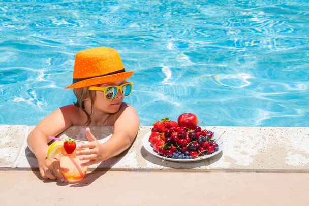 Gyerek a medencében játszik a nyári vízben. Nyaralni és gyerekekkel utazni. Nyári gyümölcsök gyerekeknek - Fotó, kép