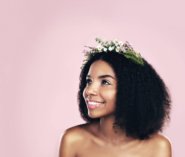 Kwiaty, korona i kobieta myśląc o pięknie w studio, różowe tło i makieta naturalnej pielęgnacji włosów afro. Twarz, szczęśliwa afrykańska modelka i marzenie na jawie z kwiatowym wieńcem, wiosenne pomysły estetyczne i ekologiczne. - Zdjęcie, obraz