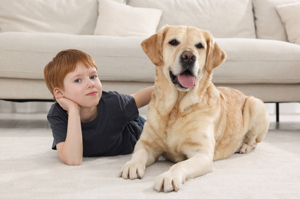 Cute child with his Labrador Retriever on floor at home. Adorable pet - Фото, зображення