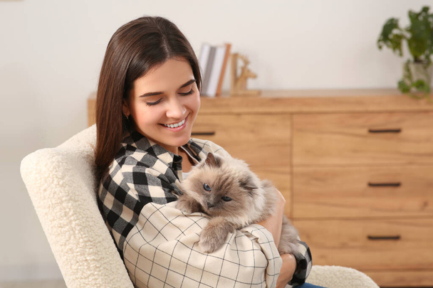 Woman hugging her cute cat on soft armchair at home - Photo, Image
