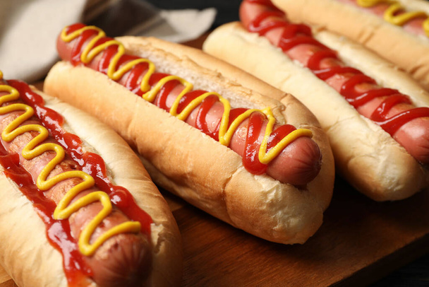 Delicious hot dogs with mustard and ketchup on wooden table, closeup - Foto, Imagem