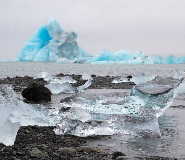 Blue Icebergs in Ocean Water. Glacier Ice Drift at Calm Water. Pure Ice Chunks from Melting Glacier. Icy Winter Landscape. Foggy Weather in Iceland.. High quality photo - Zdjęcie, obraz