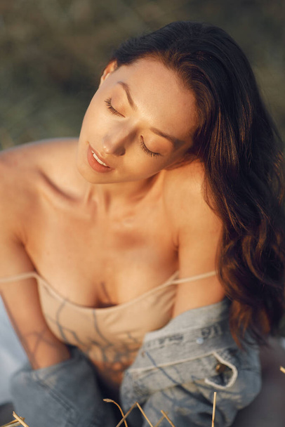 Woman in a summer field. Brunette in a brown underwear. Girl on a sunset background. - Photo, image