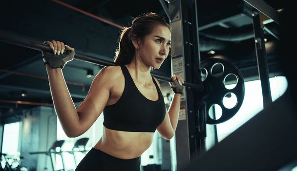 Mujer deportiva haciendo ejercicio con placa de peso en el gimnasio. - Foto, imagen