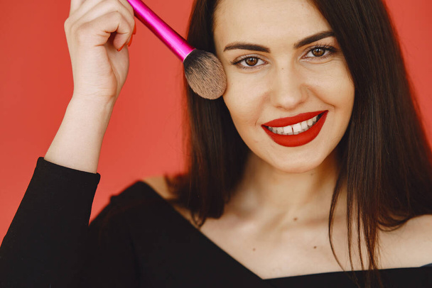 Woman with brush for make up. Girl on a red background. - Foto, Bild