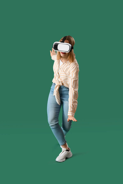 Csinos fiatal nő VR szemüveg zöld háttér - Fotó, kép