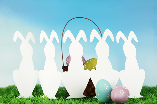 Paper Easter rabbits and eggs on green grass, on sky background - Фото, зображення