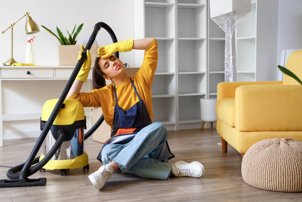 Tired young woman after hoovering floor in her house - Foto, Imagem