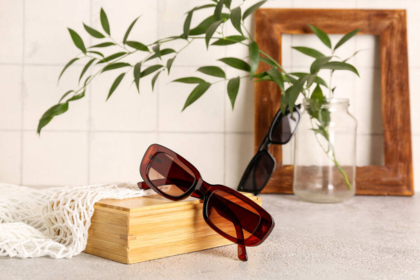 Sunglasses with wooden box and string bag on grunge table, closeup - Photo, Image