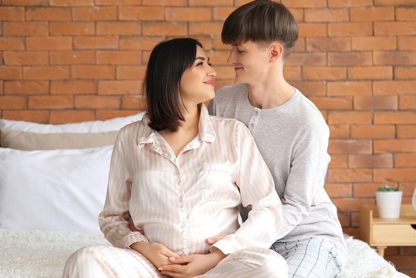 Mladý těhotný pár sedí v ložnici - Fotografie, Obrázek