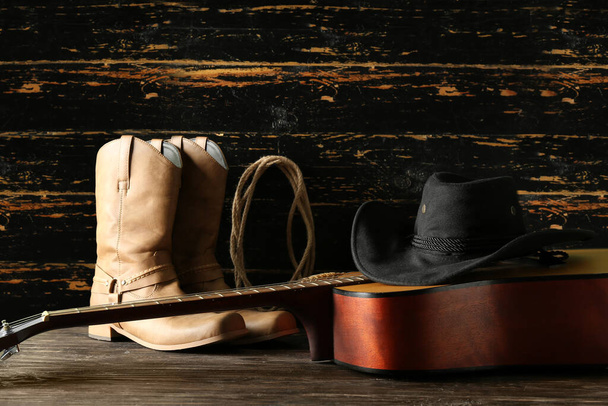 Kowbojski kapelusz, gitara i buty na drewnianym tle - Zdjęcie, obraz