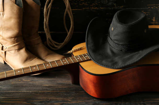 Ковбойская шляпа, гитара и сапоги на деревянном фоне - Фото, изображение