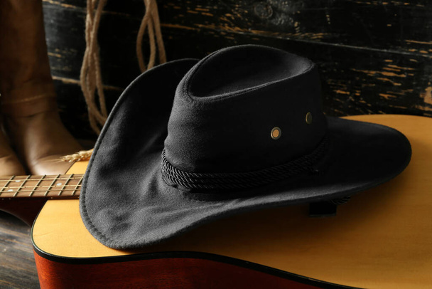 Ковбойская шляпа, гитара и сапоги на деревянном фоне - Фото, изображение