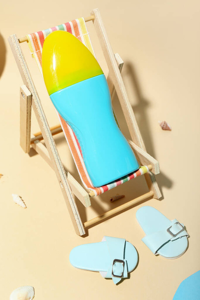Creative composition with miniature deckchair and sunscreen on beach - Photo, Image