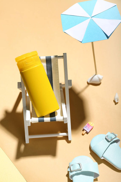 Renkli arka planda minyatür şezlonga, şemsiyeye ve güneş kremine sahip yaratıcı kompozisyon - Fotoğraf, Görsel