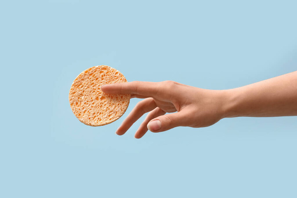 Hand with sponge for makeup removal on light blue background - Фото, зображення