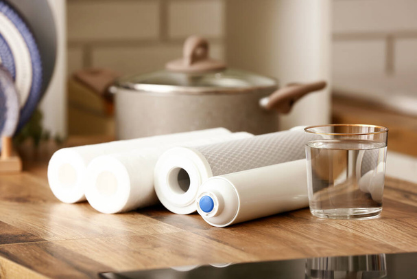 Copo de água com filtros em mesa de madeira na cozinha - Foto, Imagem