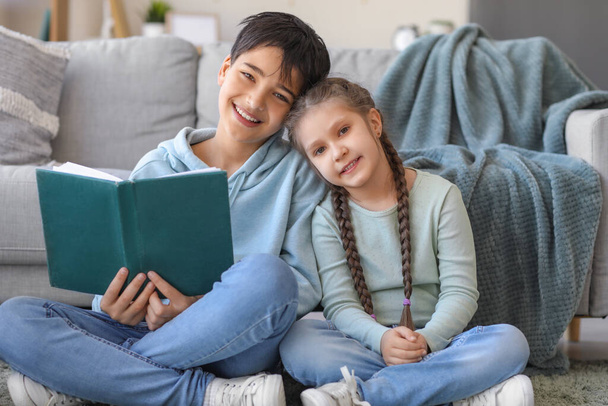 Mały chłopiec z siostrą czytający w domu - Zdjęcie, obraz
