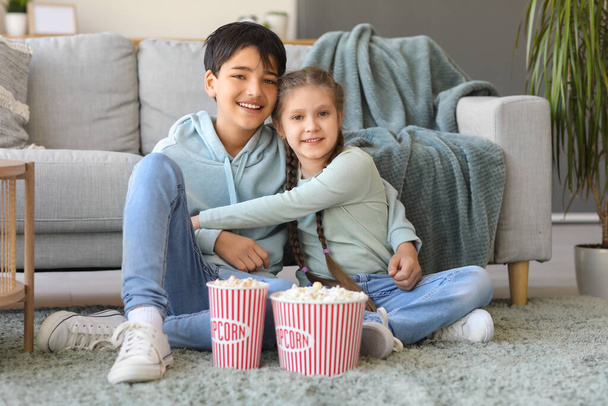 Little girl hugging her brother while watching movie at home - Foto, afbeelding