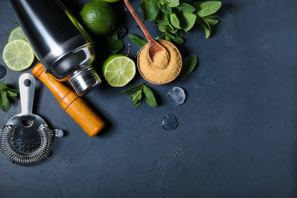 Шейкер, фильтр, раствор и ингредиенты для приготовления мохито на темном фоне - Фото, изображение