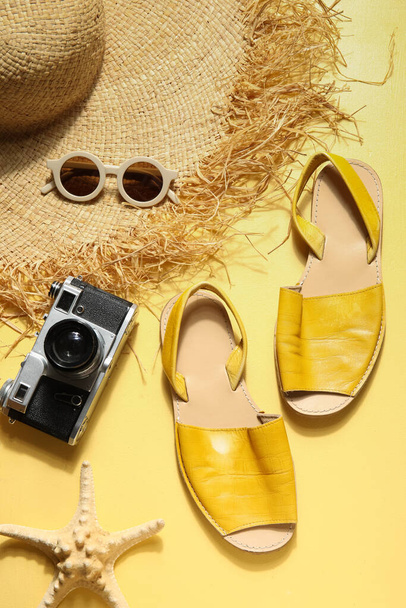 Napszemüveges szandál, fényképezőgép és fonott kalap sárga alapon - Fotó, kép