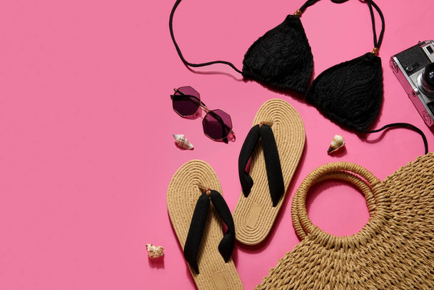Slippers met badpak, zonnebril en tas op roze achtergrond - Foto, afbeelding