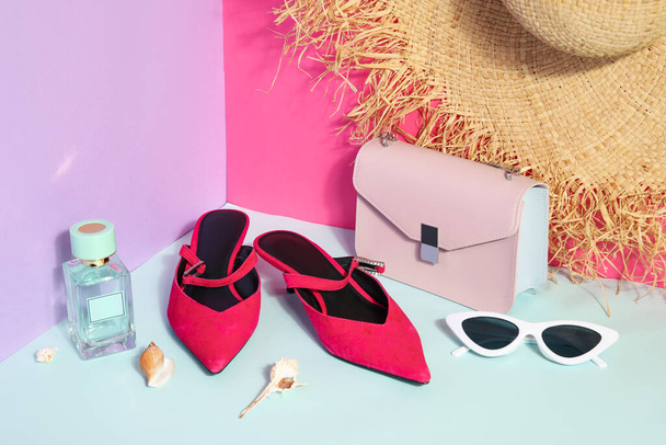 Pair of sandals with sunglasses, bag and wicker hat near color wall - Photo, Image