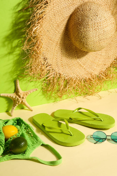 Chanclas con bolsa, gafas de sol y sombrero de mimbre cerca de la pared verde - Foto, Imagen