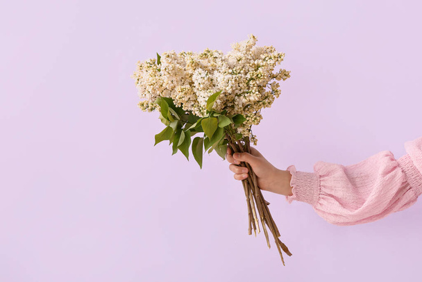 Female hand with bouquet of lilac flowers on purple background - Fotografie, Obrázek