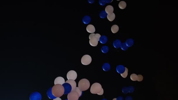 Valkoiset ja siniset ilmapallot lentävät yötaivaalle. Hidastus - Materiaali, video