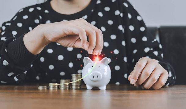 Hand of businesswoman holding a coin putting in piggy bank white arrow income salary rate increase to save money grows on a pile of money. Invest future,Loan, financial, investment and bonus concept. - Foto, immagini