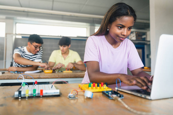 Γυναίκα Φοιτητής προγραμματισμού ηλεκτρονικών κυκλωμάτων πίνακα στο μάθημα μηχανικής - Κορίτσι τεχνολογίας στο σχολείο - Φωτογραφία, εικόνα