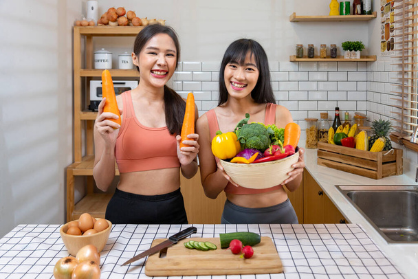 Azjatycka siostra ma zdrowe jedzenie i picie, pomagając sobie nawzajem gotowanie w kuchni dla wegańskie, wegetariańskie i roślinne składnik - Zdjęcie, obraz