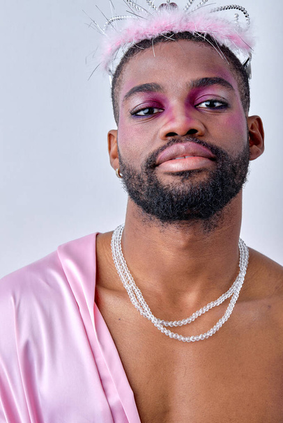 close-up Portrait of 20s black man in crown and pink sweet shirt posing at camera. American Gay wear fashion style isolated over white studio Background. beauty, fashion, models, lgbt concept. - Zdjęcie, obraz