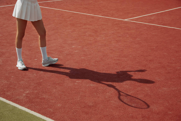L'ombra del giocatore sul tappeto del campo da tennis durante la partita. Una donna gioca a tennis professionalmente. Attività ricreative. Giocatore di tennis in azione. - Foto, immagini