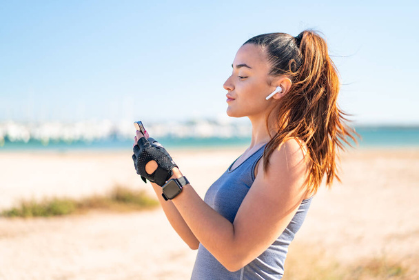 Young pretty sport woman wearing sport wear and listening music with phone - Fotografie, Obrázek