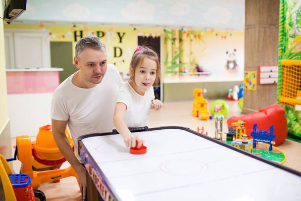 father and daughter have fun and play at the children's creative center, play air hockey. - Photo, Image