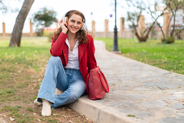 Jeune femme caucasienne à l'extérieur écouter de la musique - Photo, image