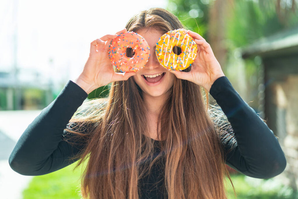 Young pretty caucasian woman holding donuts in eyes - Фото, зображення
