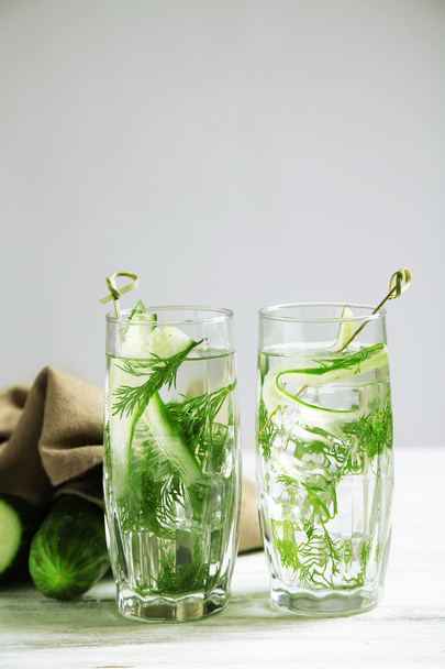 Glasses with fresh organic cucumber water on wooden table, on grey background - Фото, изображение