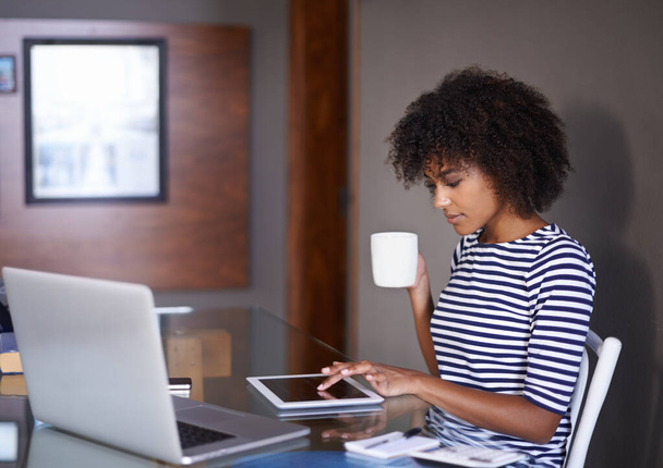 Laptop, tablet and woman with coffee for work from home opportunity, freelancer career and multimedia planning. African person or remote worker drinking tea with inspiration for digital tech project. - Photo, Image