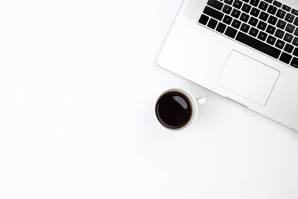 Minimalistic white background with a laptop and a cup of black coffee, top view, copy space. - Photo, Image